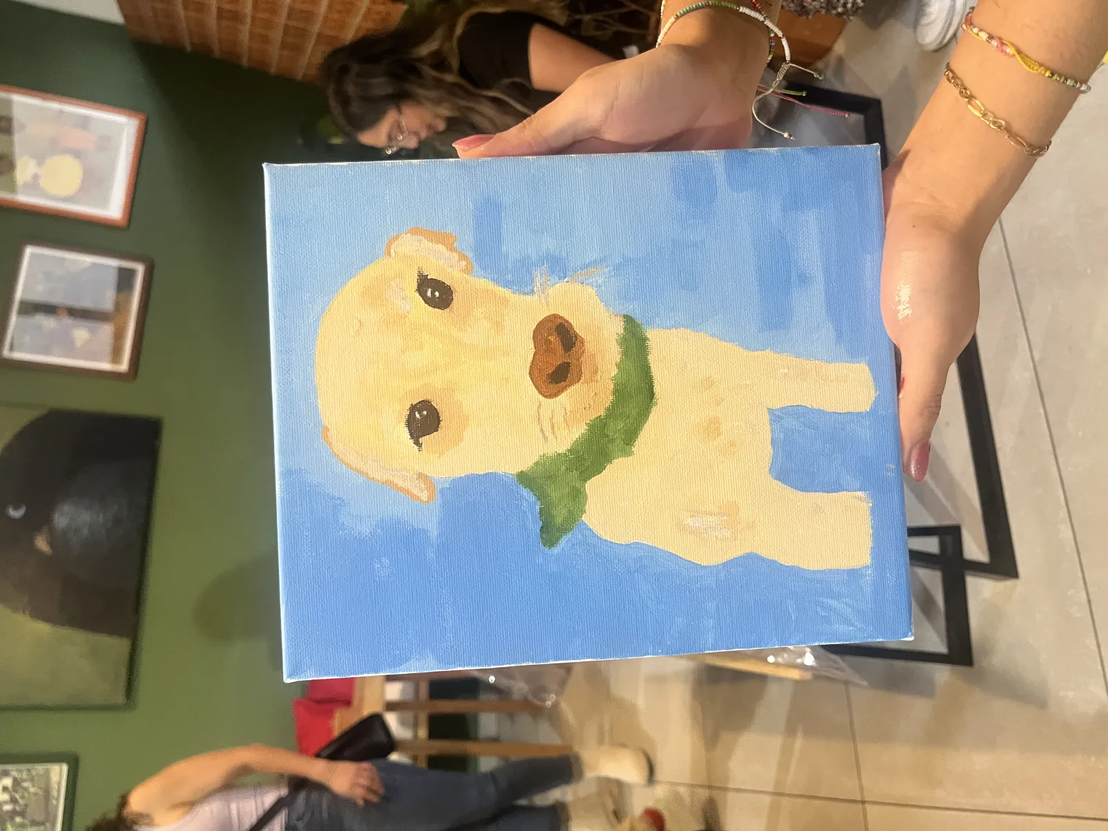 Manos sostienen el retrato en gouache de un perro labrador pintado en taller