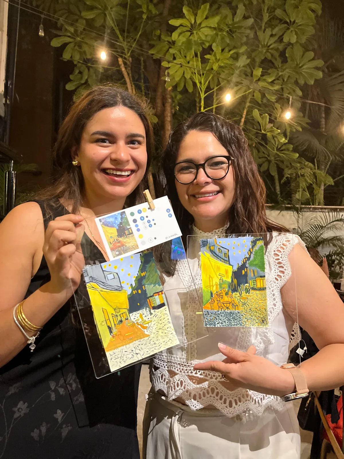 Dos asistentes sostienen sus versiones de la Terraza de café de Van Gogh en un taller nocturno