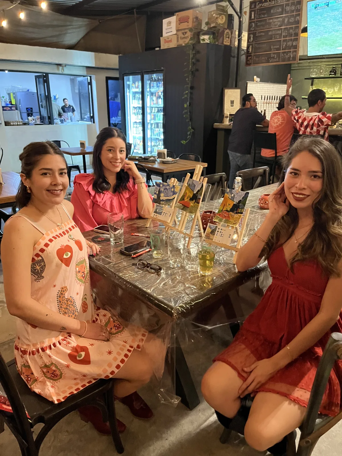 Tres asistentes disfrutan una tarde de pinta y brinda alrededor de una mesa